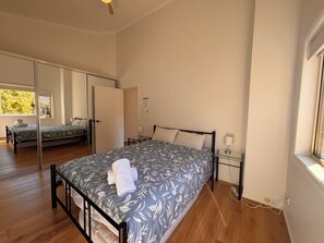A bedroom with a bed, bedside tables, a mirror, and a window.