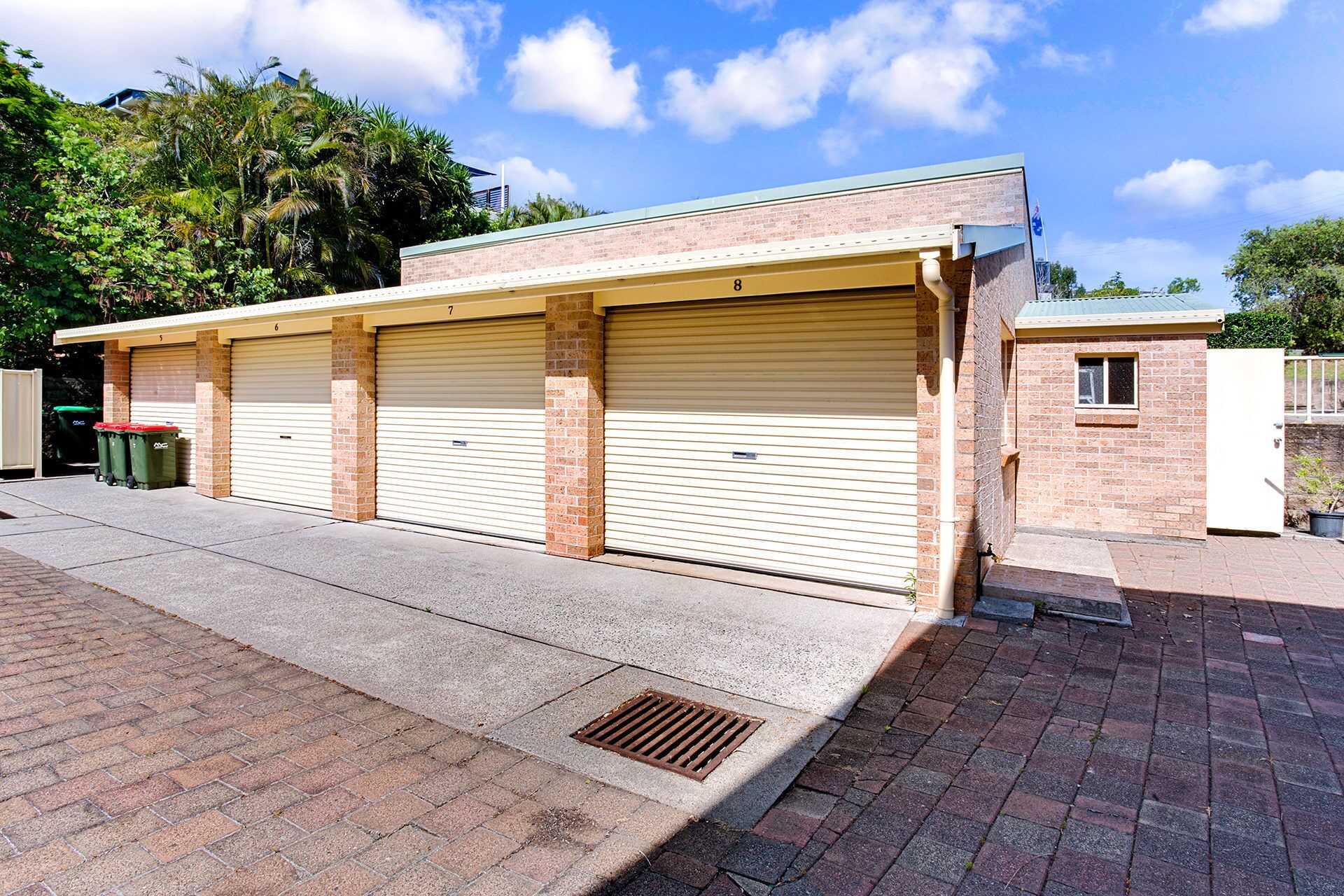 A building with three garage doors, numbered 5, 6, and 7, and a small window on the right.