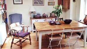 Ein Essbereich mit einem Holztisch, Stühlen, einer Blumenvase, einem Bücherregal und einem Schrank.