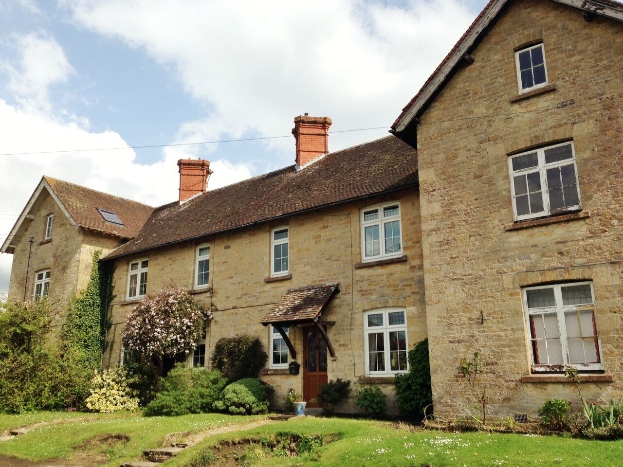 A two-story stone house with a garden in front.