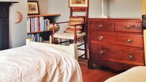 Ein Schlafzimmer mit einem großen Bücherregal, einer hölzernen Kommode, einem Sessel und einem Bett.