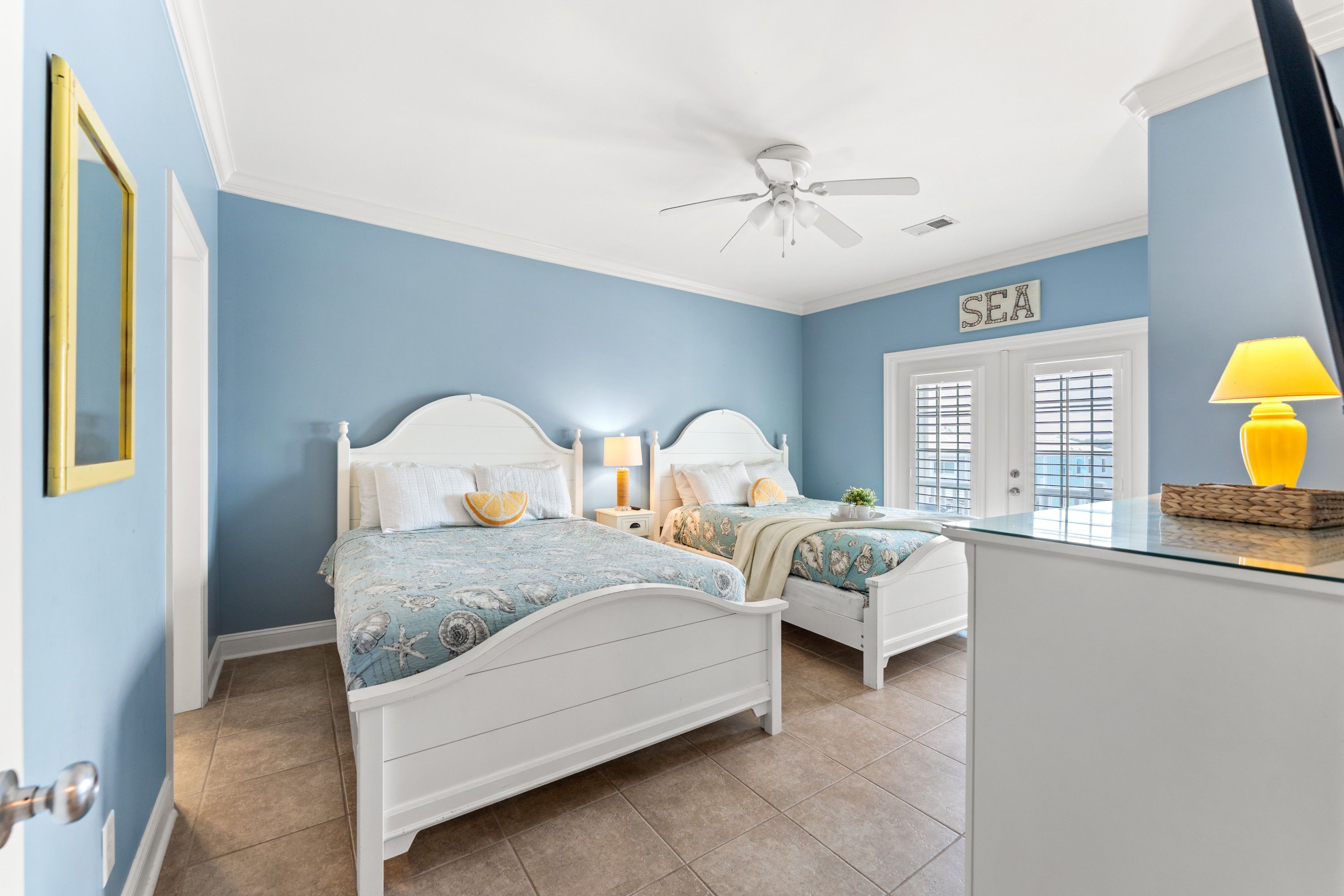 A bedroom with two beds, a ceiling fan, and a window with blinds.