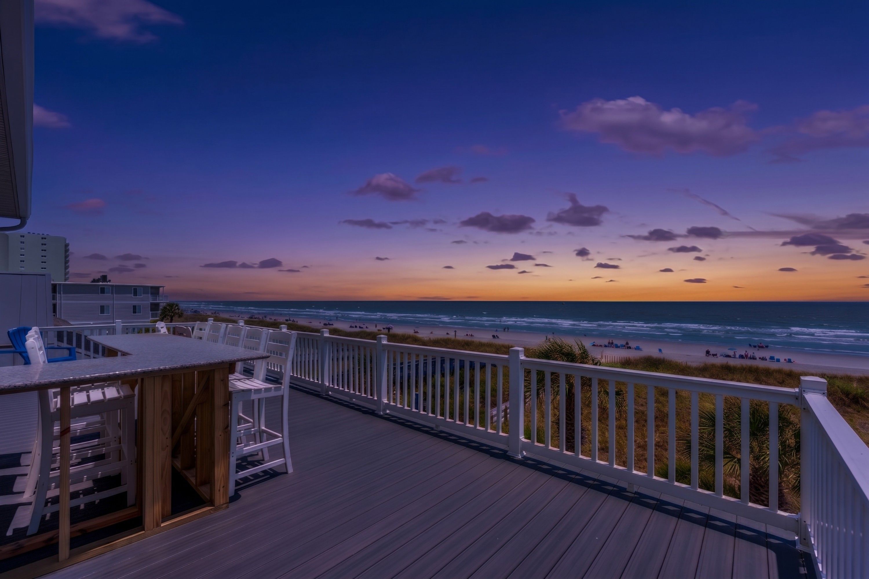Una terraza con vistas a la playa y al océano durante el atardecer.