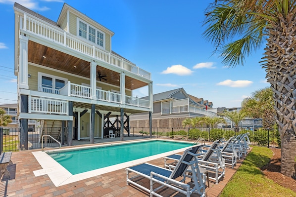 A two-story building with a pool and outdoor seating. - Landshark, Luxury Oceanfront Cherry Grove Home with Game Room and Pool (North Myrtle Beach)