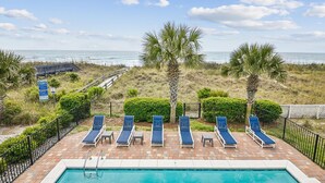A pool area with lounge chairs and a view of the ocean. - Landshark, Luxury Oceanfront Cherry Grove Home with Game Room and Pool (North Myrtle Beach)