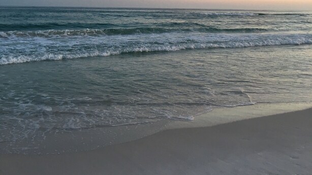 Ein Strand mit Wellen und blauem Himmel.