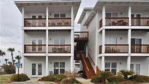 Ein zweistöckiges Motel mit einer zentralen Treppe und Balkonen auf jeder Etage sowie einer gepflasterten Auffahrt.