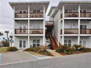Stunning two-story building with a central staircase and accessible entrance, surrounded by lush greenery and a paved walkway.
