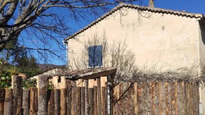 A rustic building with a tiled roof, a wooden fence, and a concrete pathway leading to the entrance. - house for 4 to 6 persons fenced garden (Sainte-Jalle)