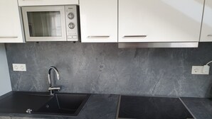 A modern kitchen with a double sink, a built-in microwave, and a stainless steel range hood. - Limburg: TOP apartment 75 sqm with balcony in quiet vorz. location (Limburg an der Lahn)