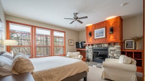 Un dormitorio con una cama grande, una silla, una chimenea y un televisor.