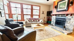 Una sala de estar con chimenea, sofás de cuero, una mesa de centro y un televisor.