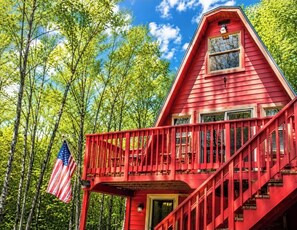 A red wooden cabin with a balcony, surrounded by trees. - Hocking Hills Cabin  Wifi, FirePit, Walking Trail . Peaceful location. (Laurelville)