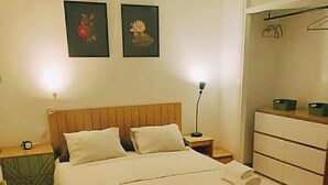 Un dormitorio con cama, mesitas de noche, ventilador de techo, cómoda y una pared con dos cuadros.