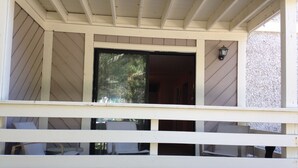 A covered porch with a white railing, a door leading inside, and a small table and chair arrangement. - 1st Floor, Updated, 5 min walk to the beach! (Hilton Head Island)