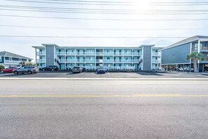 A multi-story hotel with a parking lot in front.