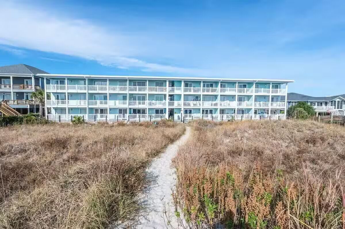 A multi-story hotel with a central pathway leading to the entrance.