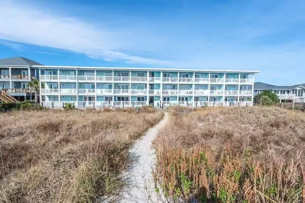 A multi-story hotel with a central pathway leading to the entrance. - Oceanfront Cherry Grove 2 BR Condo - Excellent Reviews!!  (North Myrtle Beach)