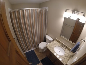 Une salle de bain équipée d’une douche, de toilettes, d’un lavabo et d’un miroir.