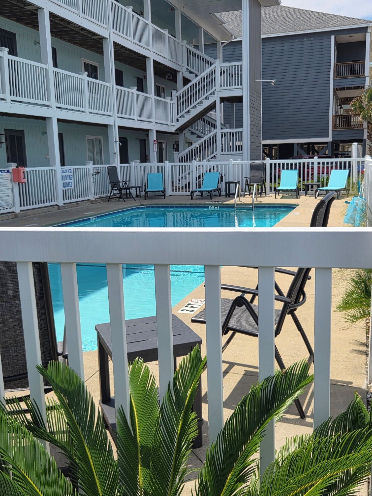 A multi-level hotel with a pool area, including lounge chairs and a staircase.