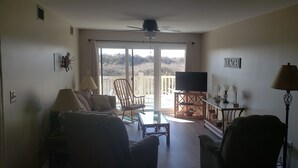 A living room with a sofa, armchairs, a coffee table, a TV, and a balcony with a view. - Oceanfront Cherry Grove 2 BR Condo - Excellent Reviews!!  (North Myrtle Beach)