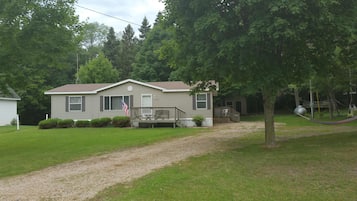 A single-story house with a front porch, a small deck, and a flag.