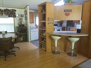 Una cocina con armarios de madera, un refrigerador blanco y una zona de bar con dos taburetes.