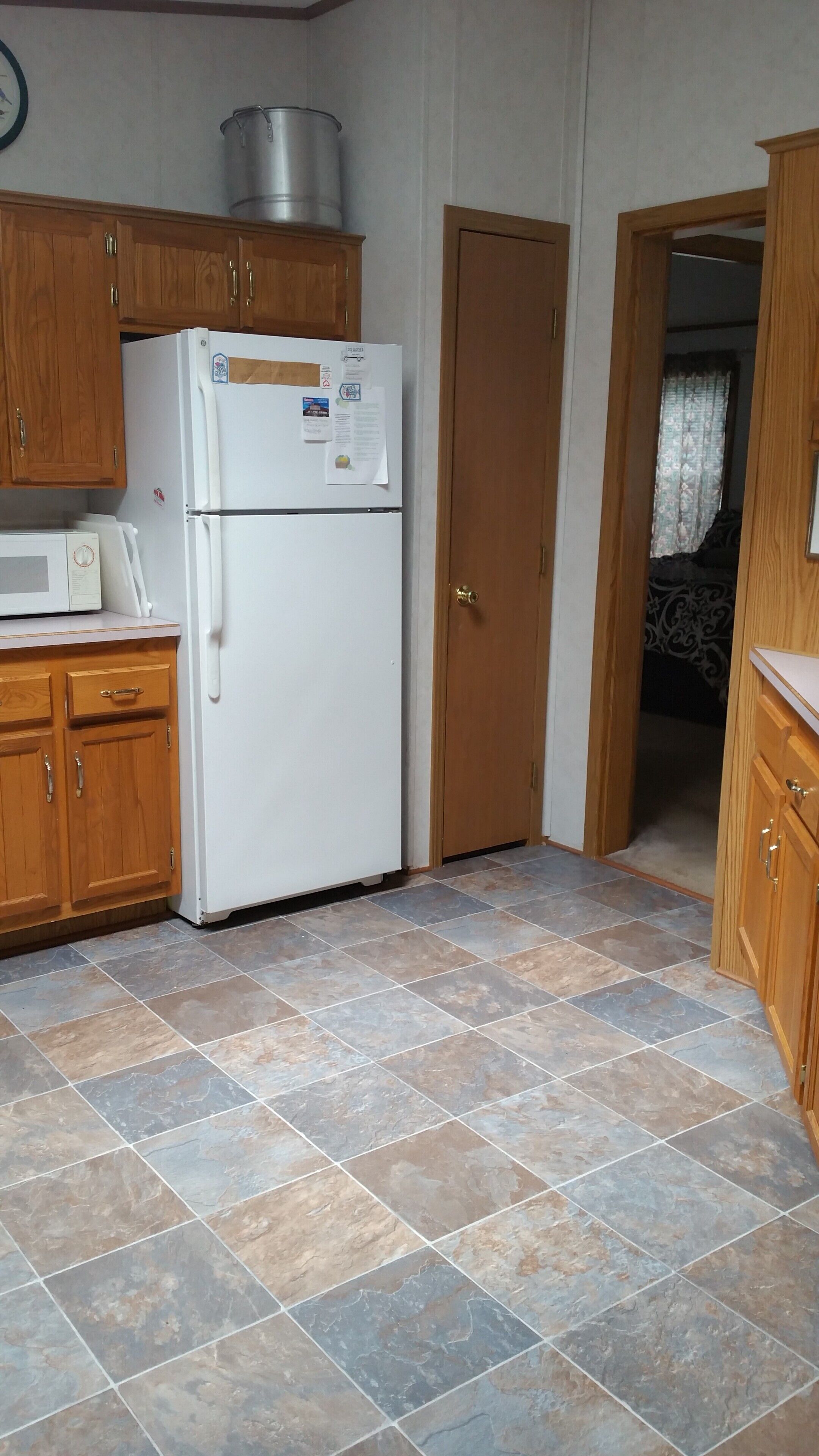 A compact kitchen with wooden cabinets, a white refrigerator, and a microwave.