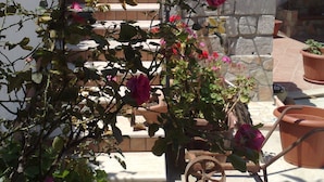 Un jardin avec un banc, des plantes en pot et un mur de pierre.