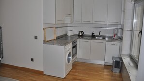 A compact kitchen with white cabinets, a built-in washing machine, a coffee maker, and a kettle. - Calle quinta D, Historic Center of Salamanca, new apartment (Salamanque)