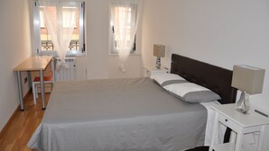 A bedroom with a bed, bedside tables, a desk, and a chair. - Calle quinta D, Historic Center of Salamanca, new apartment (Salamanque)