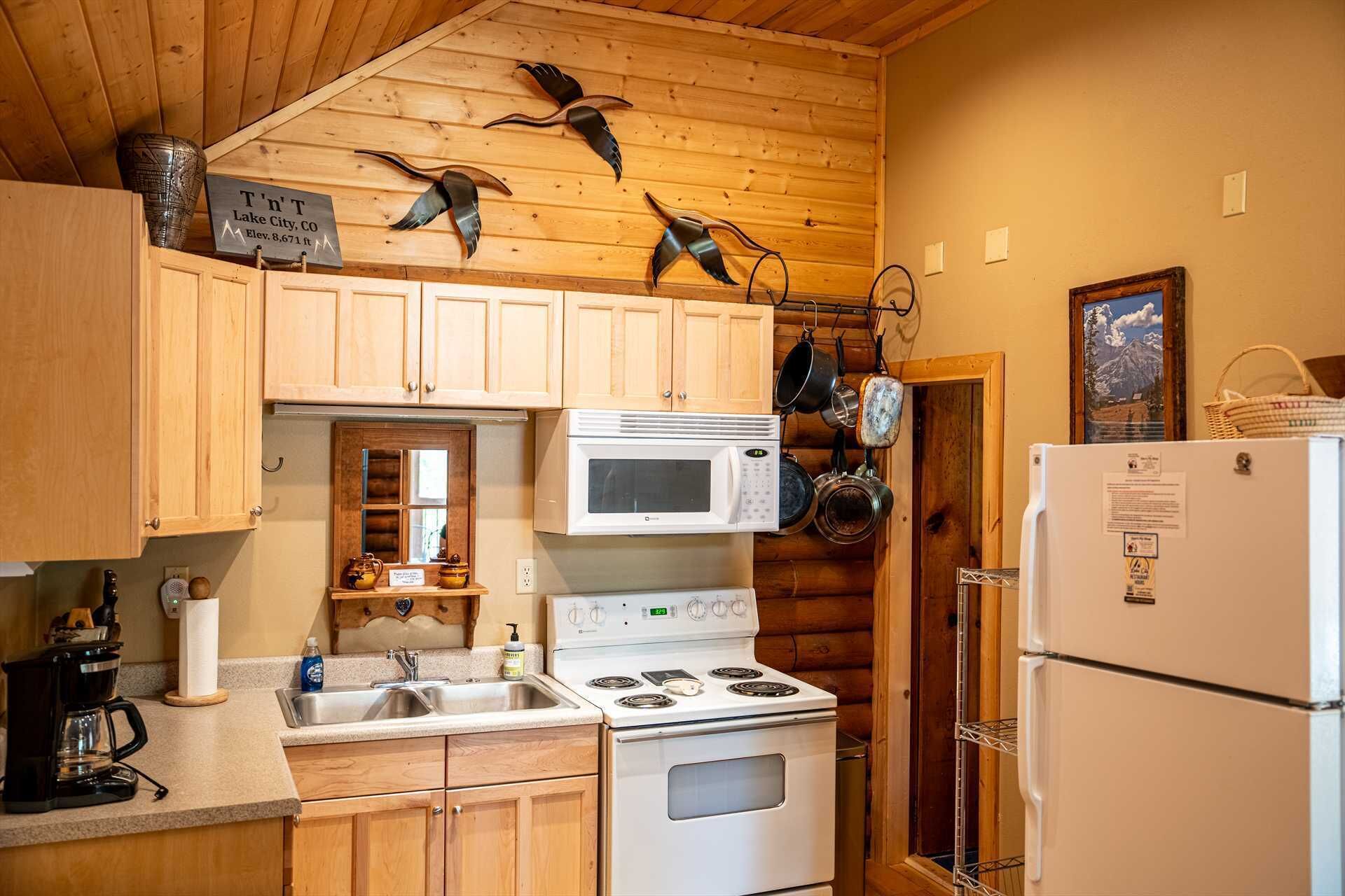 Une cuisine avec des meubles de rangement en bois, une cuisinière, un four à micro-ondes et un réfrigérateur.
