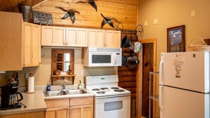 Una cocina con armarios de madera, estufa, microondas y refrigerador.