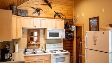 Une cuisine avec des meubles de rangement en bois, une cuisinière, un four à micro-ondes et un réfrigérateur.