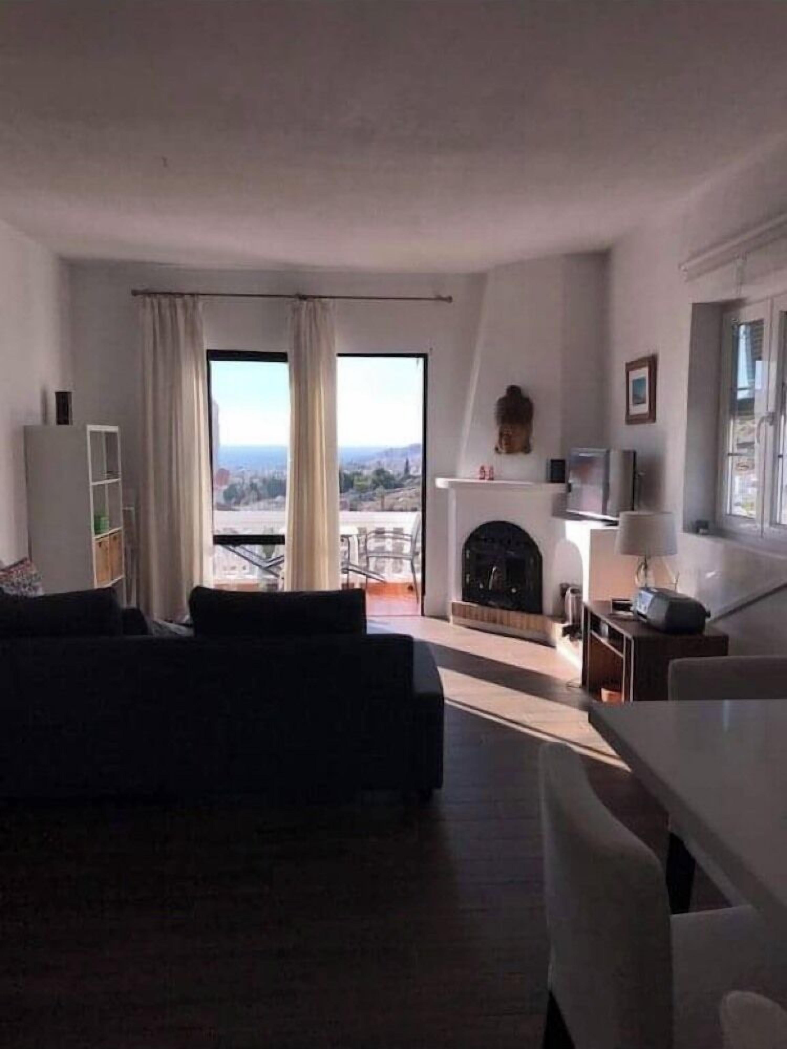 A modern living room with a sofa, a fireplace, and a view of the city.