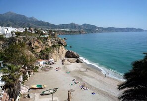 A coastal beach with rocky cliffs, a clear blue sea, and a few people enjoying the sun. - Amazing views from 3 large terraces, views over the sea, mountain and Nerja city (Nerja)