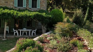 A stone building with a garden patio, outdoor seating, and a bench.