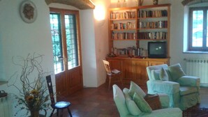 A living room with a bookshelf, a television, and two armchairs.