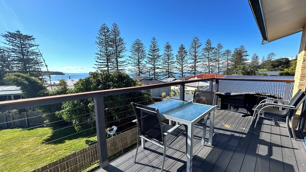 A wooden deck with a table and chairs, overlooking a grassy area and trees. - Pet Friendly, Magnificent Ocean Views, A minutes' Easy Stroll To The Beach (Black Head)