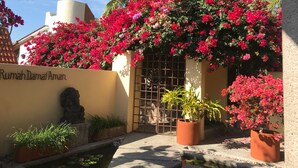 A courtyard with a water feature, potted plants, and a wall with a name plaque.