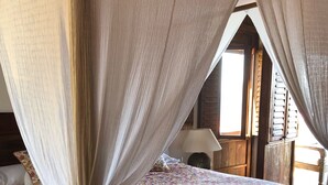 A bed with a floral bedspread, a canopy, and a wooden headboard.