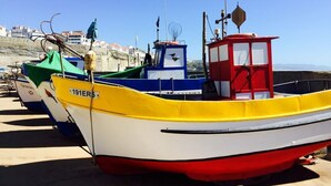 Une rangée de bateaux aux couleurs vives est amarrée à un quai, avec des bâtiments en arrière-plan.