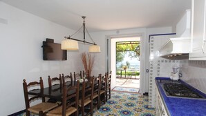 A dining area with a wooden table and chairs, a chandelier, and a view of the outdoors through a glass door. - Borgo antico 1, Romantic Amalfi Villa Amalfi With Stunning Sea View, gardens (Amalfi)