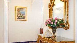 A hallway with a framed painting, a mirror with a gold frame, and a vase with pink flowers on a glass table. - Borgo antico 1, Romantic Amalfi Villa Amalfi With Stunning Sea View, gardens (Amalfi)