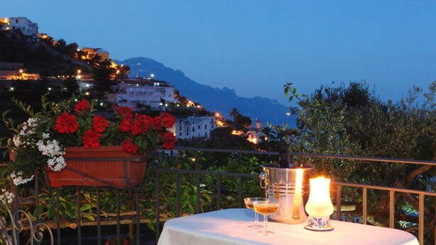 A terrace with a table set for dining, overlooking a hillside with buildings and a mountain in the background. - Borgo antico 1, Romantic Amalfi Villa Amalfi With Stunning Sea View, gardens (Amalfi)