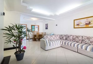 A living room with a sectional sofa, a dining table with chairs, a potted plant, and a framed picture on the wall. - House in the center of Paraty with swimming pool. (PARATI)