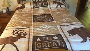 A bed with a quilt featuring animal prints and motivational phrases.