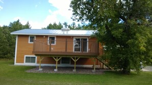 A two-story house with a wooden deck and a small balcony.