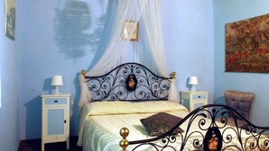 Une chambre à coucher avec un lit à baldaquin, des tables de chevet et un fauteuil.