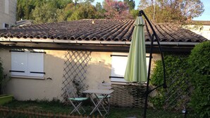 A house with a tiled roof, a small patio with a table and chairs, and a green umbrella. - HOLIDAY COTTAGE FURNITURE (Saint-Michel-De-Fronsac)